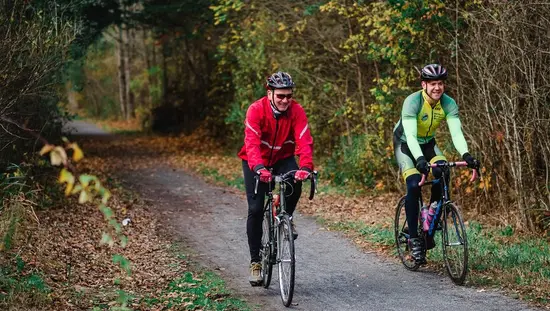 Two men smiling and cycling on a trail