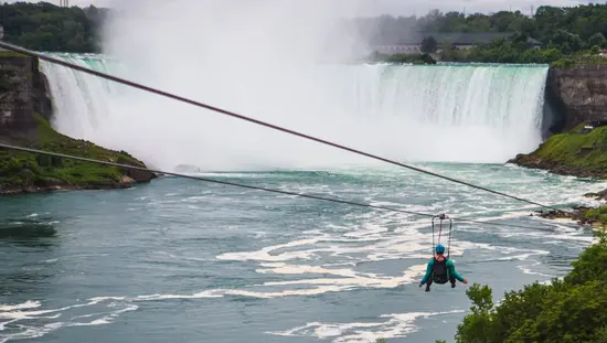 Una persona que te baja por una tirolesa frente a las Cataratas del Niágara.