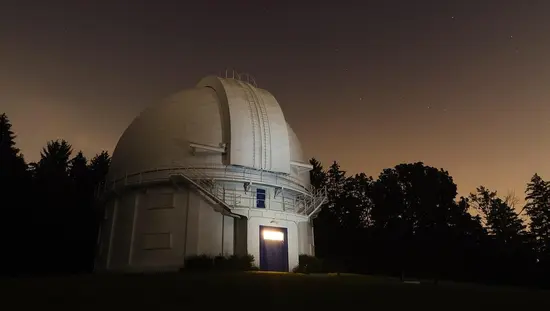 Un ciel sombre avec des étoiles entoure le bâtiment gris de l'observatoire