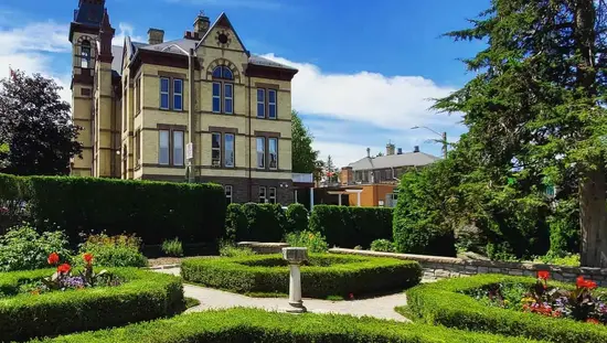 Des haies bien entretenues encadrent plusieurs jardins floraux situés à l'avant d'un grand domaine