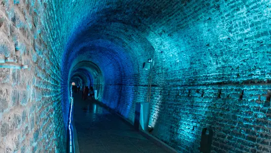 Blue light illuminates a stone tunnel.