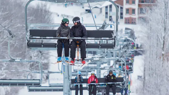 Mehrere Skifahrer fahren mit dem Skilift im Skigebiet Mount St. Louis Moonstone.