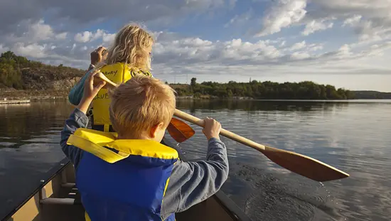 Una mujer y su hijo pequeño remando en una canoa en un día de verano en el norte de Ontario.