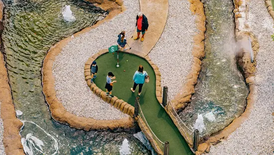  Las familias juegan al minigolf entre esculturas de dinosaurios y cascadas en Dinosaur Adventure Golf en las Cataratas del Niágara.
