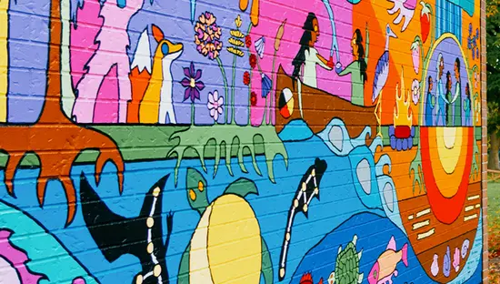 Ein Paar geht im Herbst an einem farbenfrohen Wandgemälde im Freien in der Nähe der Art Gallery of Algoma vorbei.