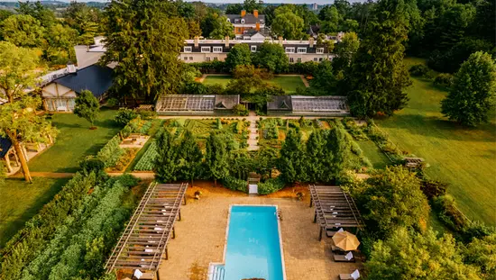  Luftaufnahme von Langdon Hall in Cambridge, Ontario, mit einem formellen Garten, einem Außenpool und einem historischen Landsitz, umgeben von Wald.