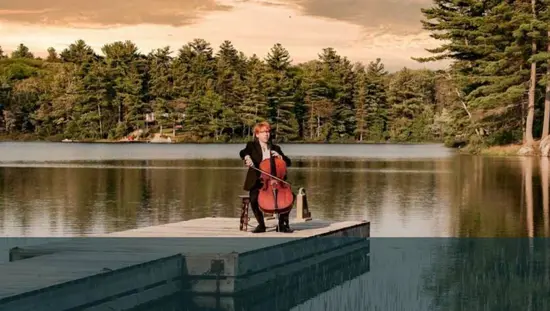 Un homme jouant du violoncelle sur un petit quai flottant entouré de forêt à Parry Sound.