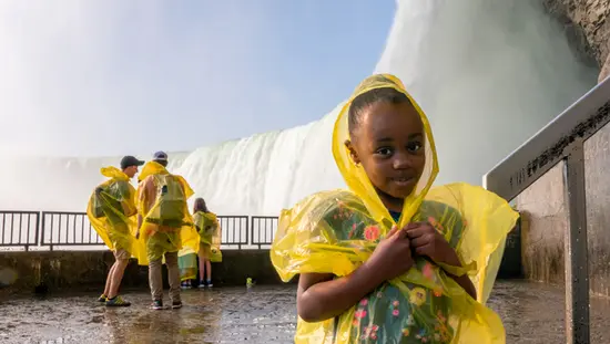 어린 소녀를 포함한 관광객들은 나이아가라 폭포의 안개로부터 자신을 보호하기 위해 폰초를 입습니다.