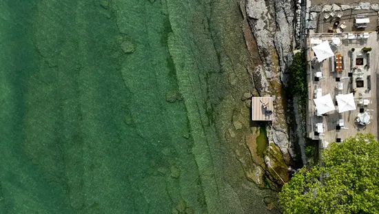 Aerial view of the sunny deck at the Lakeside Motel facing the rocky shore and aqua coloured Lake Ontario.