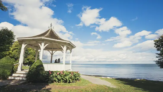 Two people in a white gazebo in Queen's Royal Park in Niagara-on-the-Lake looking out to Niagara River.