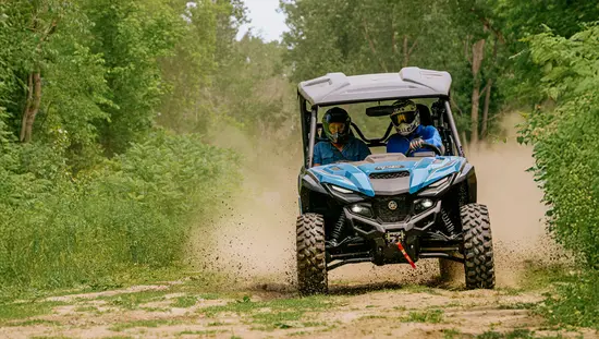 Menschen fahren an einem Sommertag in Tweed, Ontario, mit einem Geländefahrzeug auf einem von Wald umgebenen Pfad.
