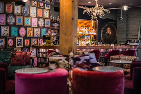 Interior de Secrette, un bar escondido en Toronto, con sillas de terciopelo, arte ecléctico y un ambiente acogedor y colorido.