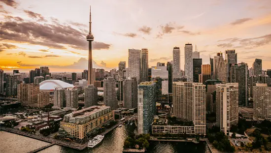 ドラマチックな空を背景に CN タワーとダウンタウンがそびえ立つ、港から見たトロントの街並み。
