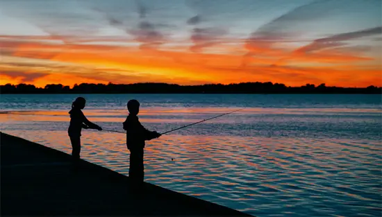 Two people fishing on a dock at sunset on Lake Erie in Leamington.