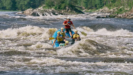 A group of people whitewater rafting on the Ottawa River with Wilderness Tours guides.