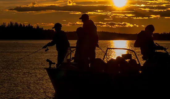 Three people fishing at sunset from a boat in Fushimi Provincial Park. 