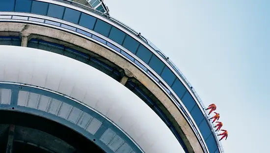 Four people are harnessed to the outside rim at the top of Toronto’s CN Tower on the EdgeWalk tour.