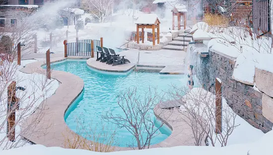 Steam rises above the outdoor water circuit surrounded by snow at Scandinave Spa.