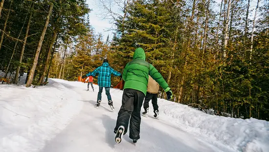 Children race along the snowy ice trail through the forest.