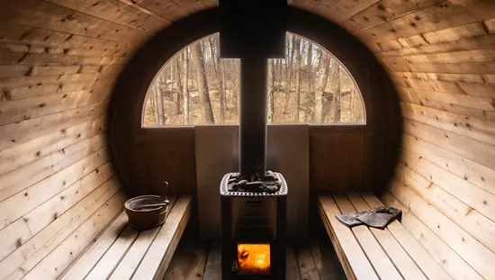 장작불과 뜨거운 돌이 놓인 삼나무 통 사우나 벤치 위에는 양동이와 장갑 한 켤레가 놓여 있다. 