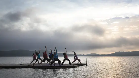 A group of people doing yoga on a wooden dock facing the lake in Northern Ontario.