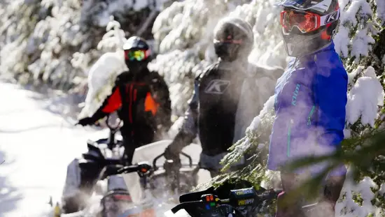A group of three snowmobilers takes a break from riding on an OFSC trail near Timmins.