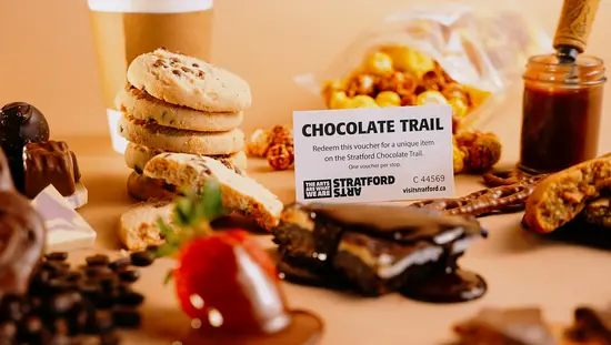 Eine einzigartige geometrische Erdbeer-Schokoladentafel vor pastellfarbenem Hintergrund, bestreut mit getrockneten Erdbeeren und Beerenstücken.