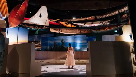 A woman explores a gallery of watercraft, including heritage canoes and kayaks, on a behind-the-scenes tour at the Canadian Canoe Museum.