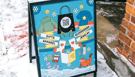 Letrero ilustrado para acera que promociona tiendas y eventos locales, ubicado en una acera nevada.