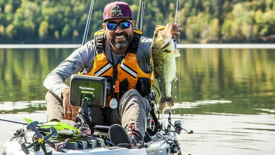 Un pêcheur brandit un poisson qu'il a attrapé depuis son kayak.
