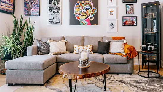 Moderna sala de estar con sofá seccional, mesa de café y obras de arte coloridas exhibidas en las paredes.