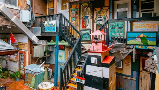 Patio al aire libre lleno de coloridos murales, esculturas e instalaciones de arte rodeado de edificios de ladrillo.