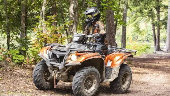  Une personne portant une tenue de camouflage et un casque conduit un VTT sur un chemin de terre dans le nord-est de l'Ontario.