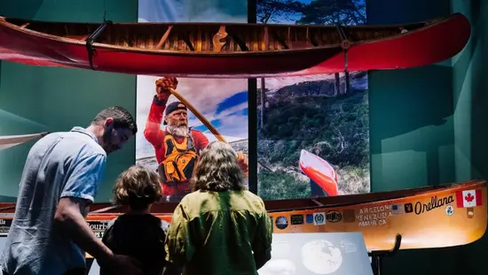 Museumsgalerie mit Kanus und Kajaks, die über den Ausstellungsstücken von der Decke hängen.