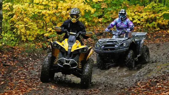Two ATV riders explore a muddy trail on a guided ATV tour in Northeastern Ontario.