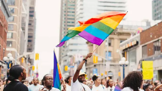 한 남성이 토론토 시내에서 프라이드 행사를 기념하는 행렬에 참여하며 무지개 깃발을 흔들고 있습니다.
