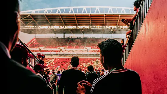 Soccer players walking through a stadium tunnel toward the field before a match.