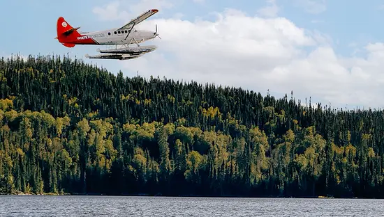 Hydravion planant au-dessus d’un lac bordé d’une vaste forêt qui transporte des chasseurs dans un lieu de chasse éloigné dans le Nord de l’Ontario.