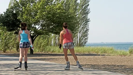 Zwei Frauen fahren auf Rollschuhen den Weg im Confederation Beach Park entlang.