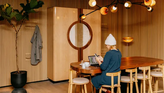 木製パネル張りの部屋で、モダンな照明の下、机に向かって仕事をしている人。