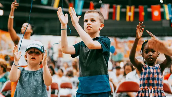 Niños pequeños aplauden durante una actividad musical en la zona infantil de un festival cultural.