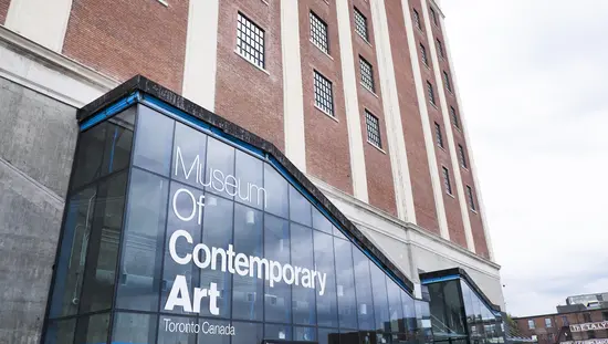 The glass entrance of the Museum of Contemporary Art Toronto, set against the historic red brick Tower Automotive Building.