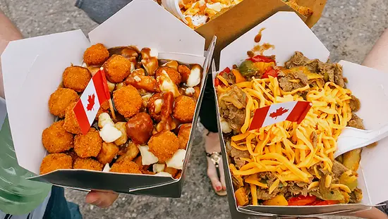 People sharing trays of poutine topped with cheese curds, gravy, and fried bites during Poutine Fest in Algoma County.