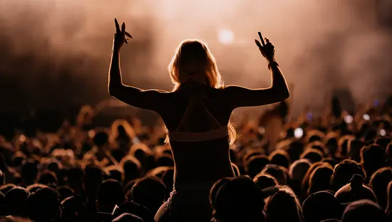 야간 야외 음악 축제 콘서트 중 군중 속에서 누군가 어깨 위에 올라타 있는 모습.