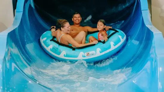Une famille profitant d'un toboggan aquatique sur une bouée au parc aquatique Adventure Bay Family Water Park.