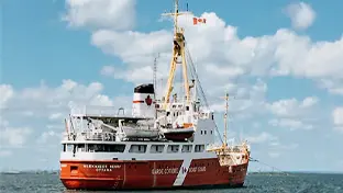 A large ship used for breaking ice, creating trading opportunities pictured in the open sea under the fluffy white clouds. 