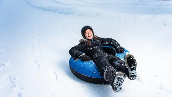 Un enfant descend la côte en bouée sur neige à Boler Mountain.