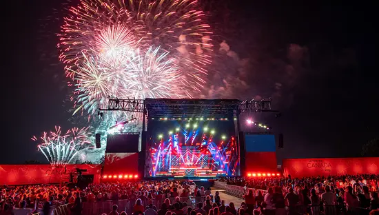 Tausende von Besuchern standen vor der Bühne der Canada Day Show auf dem Parliament Hill in Ottawa, die von Lichtblitzen und Feuerwerk erleuchtet wurde.