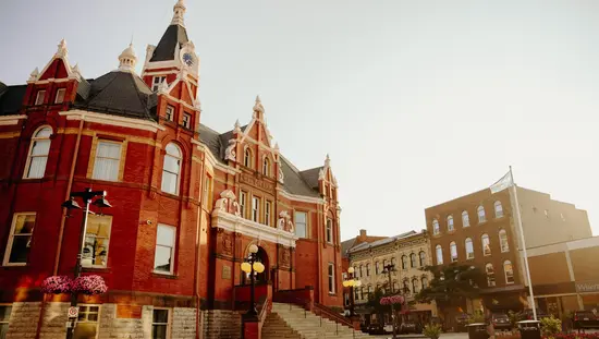 Stratford's red brick City Hall with a clock tower and Canadian flag, overlooking the downtown street below.
