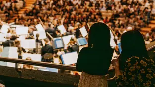 Deux spectateurs regardant un orchestre.